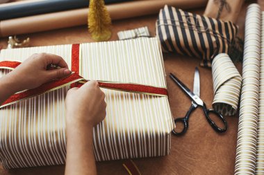 Noel hediyesi paketleme konsepti. Eller kırmızı kurdele tutuyor ve...