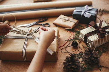 El işi kağıt ve bilim ile şık Noel hediyelerini paketleyen eller.