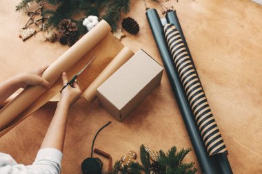 Makas ve hediye kutusuyla ambalaj kağıdı kesen eller.