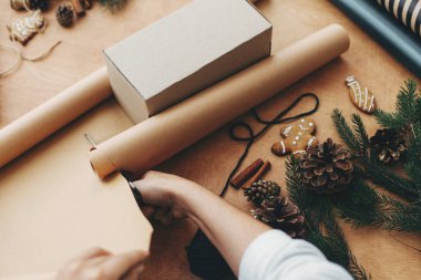 Makas ve hediye kutusuyla ambalaj kağıdı kesen eller.