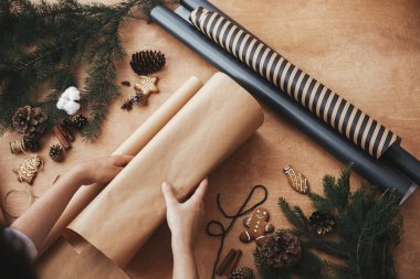 El işi kağıt ve çam dallarıyla Noel hediyesini paketleyen eller, 