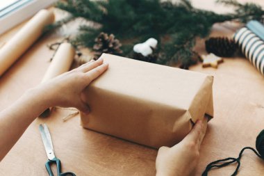 El işi kağıt ve çam dallarıyla Noel hediyesini paketleyen eller, 