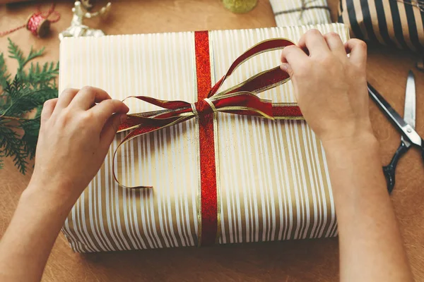 Noel hediyesi paketleme konsepti. Eller kırmızı kurdele tutuyor ve...