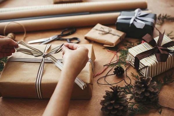 El işi kağıt ve bilim ile şık Noel hediyelerini paketleyen eller.