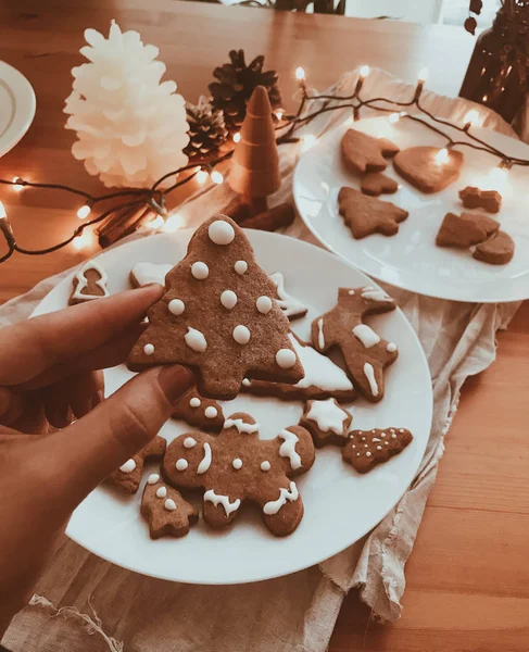 Mano tenendo pan di zenzero albero di Natale biscotto con ciliegina su bac — Foto Stock