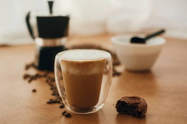 Sütlü veya kapuçinolu, cam kapta köpük ve ısırılmış makarna.