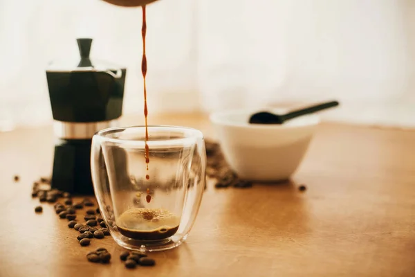 Verter el café en una taza de vidrio sobre el fondo de grano de café tostado —  Fotos de Stock