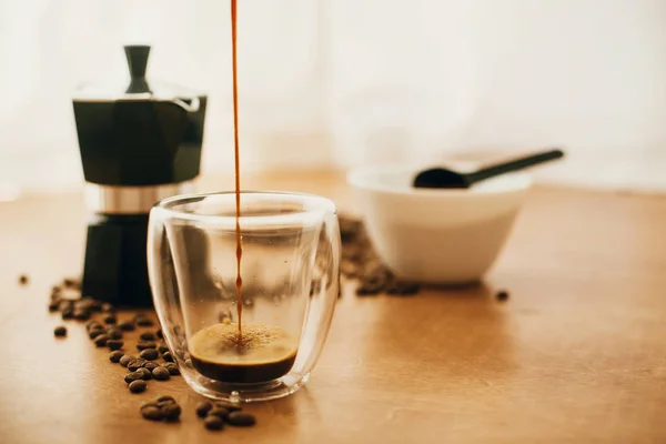 Versare il caffè in tazza di vetro su sfondo di chicco di caffè tostato — Foto Stock