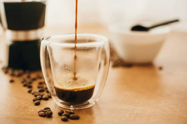 Verter café caliente en taza de vidrio sobre el fondo de café tostado —  Fotos de Stock