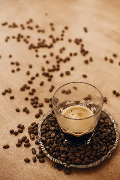 Hot espresso with foam in glass cup on vintage plate with aromat — Stock Photo, Image