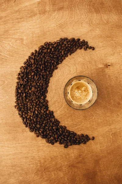 Espresso caliente con espuma en taza de vidrio y café tostado aromático —  Fotos de Stock