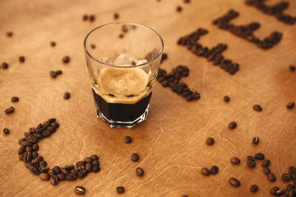 Coffee word made of aromatic roasted coffee beans and glass cup — Stock Photo, Image