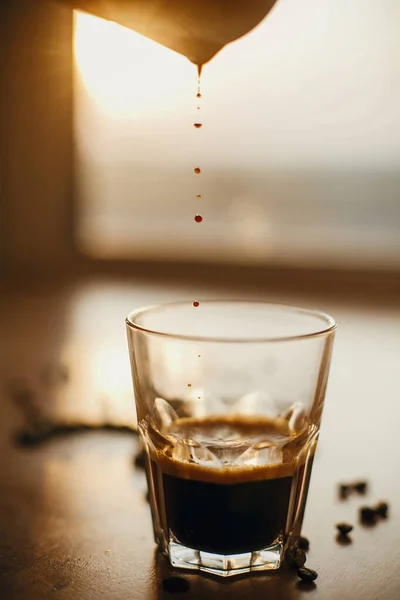 Pouring hot espresso in glass cup  in warm light on background o — Stock Photo, Image