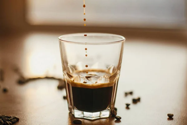 Las gotas de café se cierran en luz cálida mientras se vierte café espresso caliente i —  Fotos de Stock