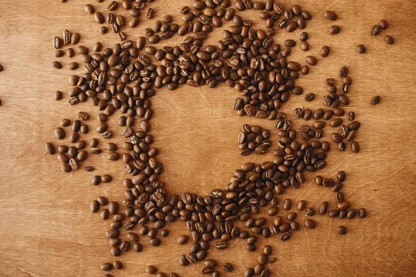 Forma de xícara de café feita em grãos de café torrados na mesa de madeira, f — Fotografia de Stock