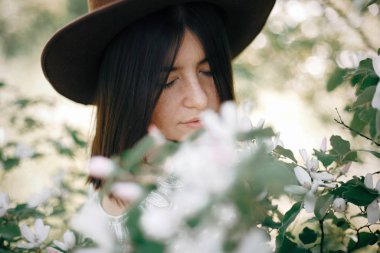 Beyaz çiçeklerin içinde duran güzel hippi kızın sakin portresi