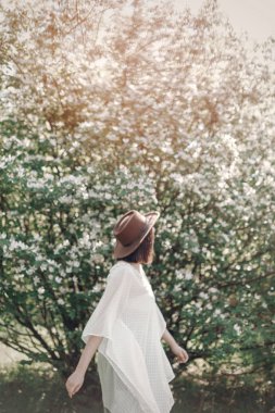 Güneşli ışıkta dans eden şapkalı mutlu bir kadının bulanık görüntüsü. 