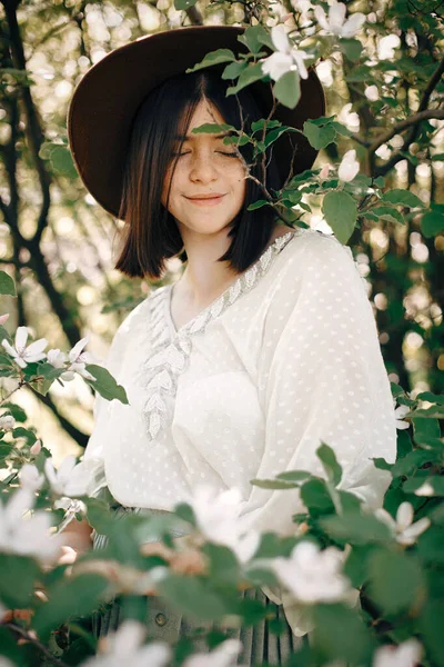 Spokojny portret pięknej hipsterki stojącej w białych kwiatach — Zdjęcie stockowe