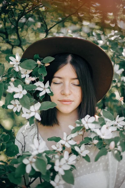Calm portrait of beautiful hipster girl standing in white blooms — Stock Photo, Image