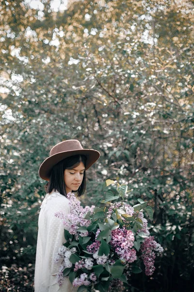 Κομψό boho γυναίκα στο καπέλο κρατώντας πασχαλινά λουλούδια μπουκέτο σε ηλιόλουστη — Φωτογραφία Αρχείου