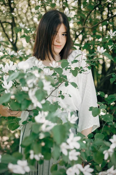 Stylische Boho-Frau posiert in weißen Blumen im Frühlingspark. hipst — Stockfoto