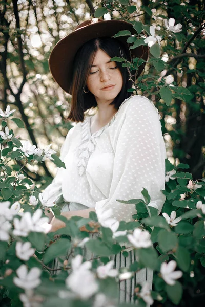 Spokojny portret pięknej hipsterki stojącej w białych kwiatach — Zdjęcie stockowe