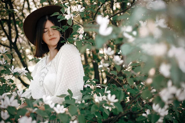 Calm portrait of beautiful hipster girl standing in white blooms — Stock Photo, Image