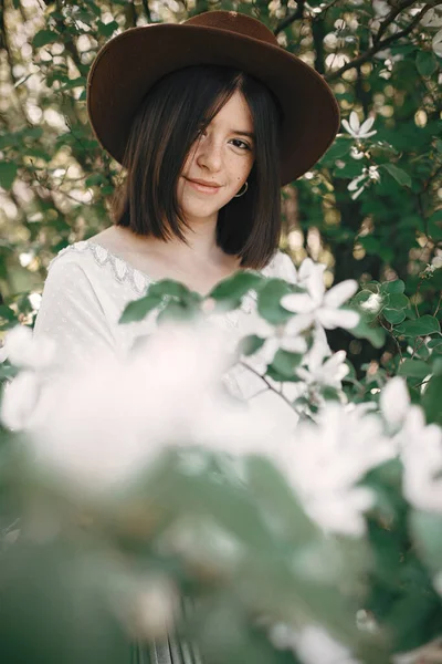 Calm portrait of beautiful hipster girl standing in white blooms Stock Image