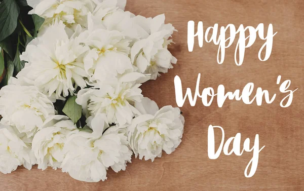 Happy women's day text on white peony flat lay on rustic wooden — Stock Photo, Image