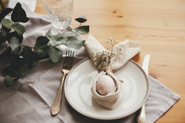 Paskalya kahvaltısı sofrasında paskalya tavşanı peçetesi içinde yumurta. Peçeteli, tavşan kulaklı, tabakta çiçekler ve çatal bıçaklı modern doğal paskalya yumurtası. Paskalya masa dekorasyonları