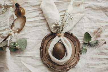 Kırsal Paskalya masa dekorasyonu, düz yatış. Peçeteli, tavşan kulaklı modern doğal yumurta, klasik tabakta çiçekler. Paskalya brançı sofrasında paskalya tavşanı peçetesinde yumurta..