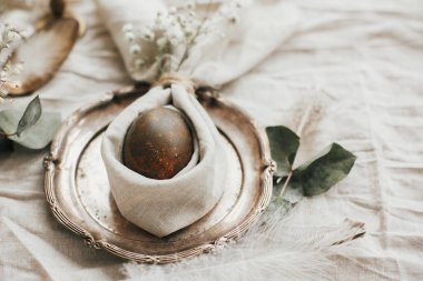 Kırsal Paskalya masa dekorasyonları. Peçeteli, tavşan kulaklı modern doğal yumurta, klasik tabakta çiçekler. Paskalya brançı sofrasında paskalya tavşanı peçetesinde yumurta..