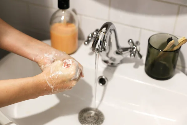 在浴室流动的水的背景上用肥皂泡沫洗手 擦手心 预防流感 个人卫生 洗手以预防大肠病毒的流行 — 图库照片