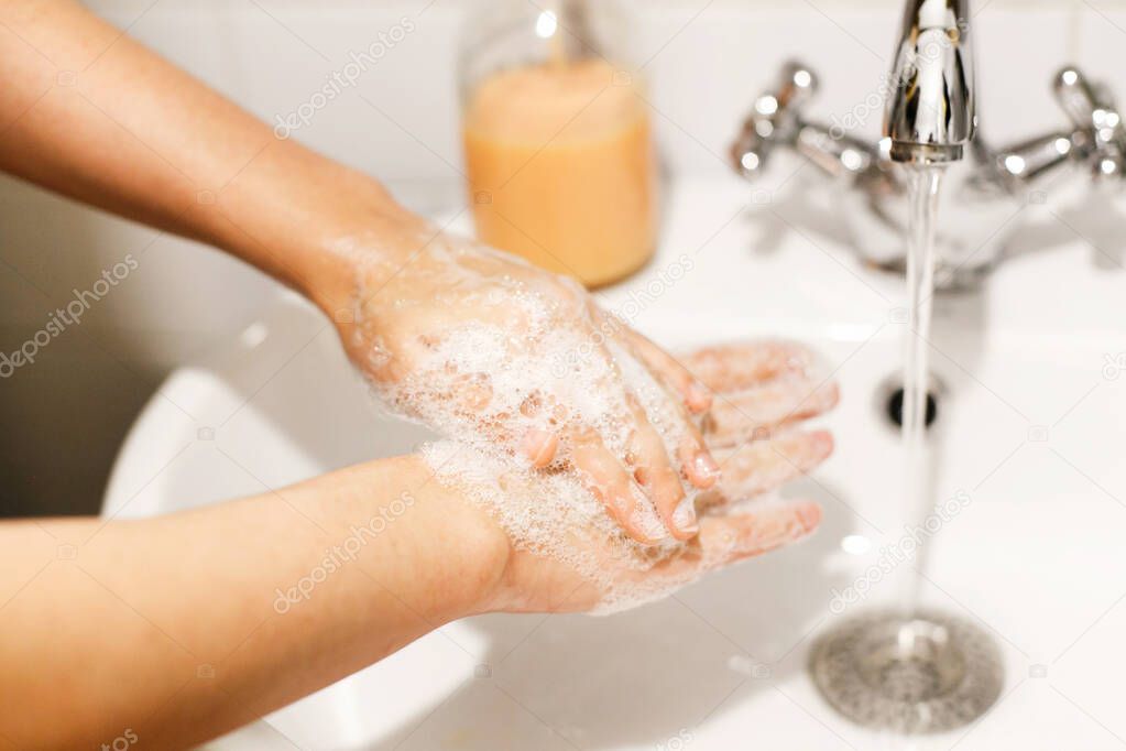 Washing hands. Hands washing with soap foam on background of water flowing from faucet. Prevention of flu disease. Personal hygiene. How to clean hands right
