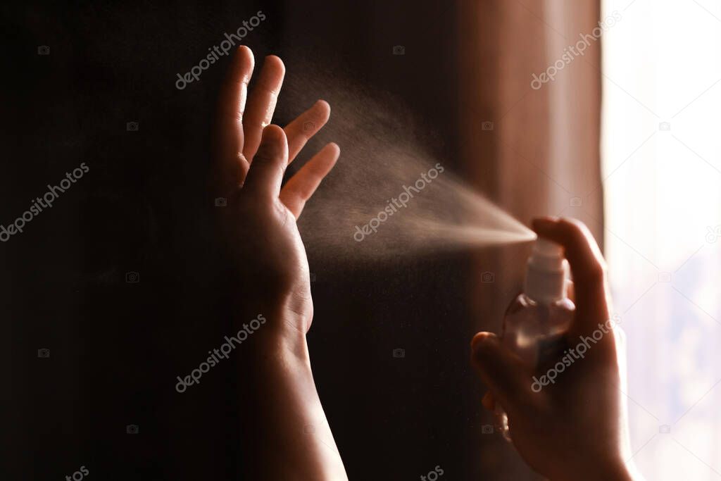 Disinfecting hands. Person using antiseptic spray on hands for prevention of flu disease or coronavirus. Personal hygiene. How to clean hands right