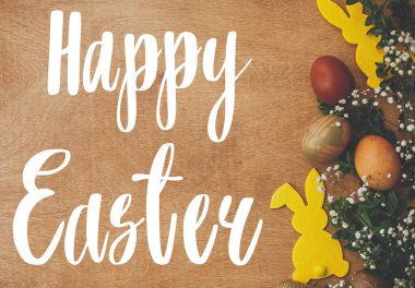 Mutlu Paskalya metinleri. Paskalya tebrik kartı. Şık paskalya yumurtaları, sarı tavşancık, kırsal ahşap masa üzerinde bahar çiçekleri. Doğal boyalı Paskalya yumurtası ve tavşan. Tatil kartı