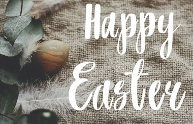 Mutlu Paskalya metinleri. Paskalya tebrik kartı. Kırsal masada tüylü paskalya yumurtası. Kırsal tekstil üzerine okaliptüs dallı doğal yeşil paskalya yumurtası. Düz yatıyordu