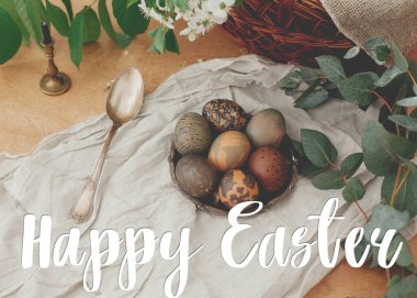 Mutlu Paskalya metinleri. Paskalya tebrik mektupları. Çağdaş Paskalya yumurtaları, bahar çiçekleri ve okaliptüsler kırsal ahşap masa üzerinde. Tebrik kartı