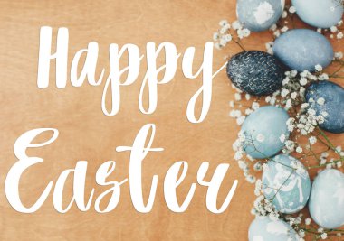 Mutlu Paskalya metinleri. Paskalya tebrik mektupları. Çiçekler ve modern Paskalya yumurtaları kırsal ahşap üzerinde yatıyordu. Renkli pastel mavi yumurtaların sınırı. Tebrik kartı