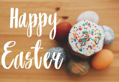 Mutlu Paskalya metinleri. Paskalya tebrik mektupları. Renkli serpiştirilmiş paskalya pastası ve kırsal masada doğal boyanmış paskalya yumurtaları. Tebrik kartı