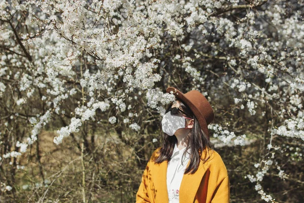 Κομψό Hipster Κορίτσι Φορώντας Μάσκα Προσώπου Και Απολαμβάνοντας Ανθισμένες Κερασιές — Φωτογραφία Αρχείου