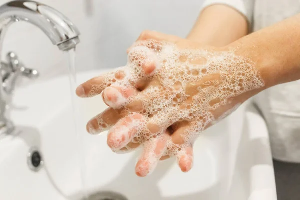 在白色浴室流动的水的背景下 用抗菌肥皂擦拭手指 预防结肠炎 清洗及消毒 — 图库照片