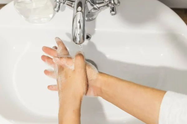 在白色浴室的流动的水的背景下 用适当的抗菌肥皂洗手 用手指擦拭顶部视图 预防结肠炎 清洗及消毒 — 图库照片
