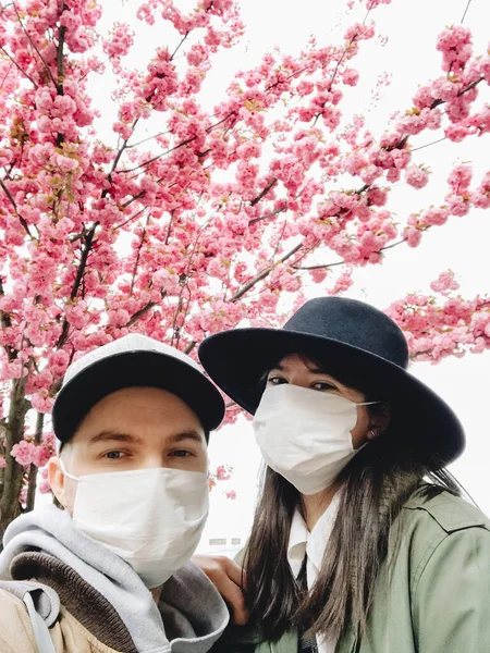 Casal Hipster Máscaras Faciais Tomando Selfie Fundo Árvores Sakura Florescendo — Fotografia de Stock