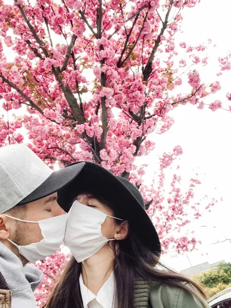 Hipster Pár Obličejových Maskách Přičemž Selfie Líbání Pozadí Kvetoucích Sakura — Stock fotografie