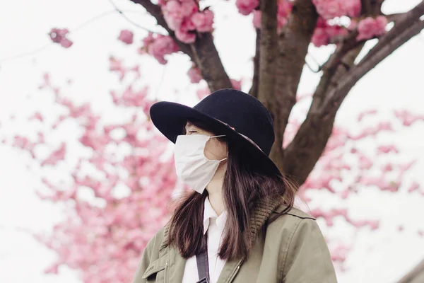 Hipsterka Masce Twarzy Stojąca Ulicy Miasta Tle Kwitnących Różowych Drzew — Zdjęcie stockowe