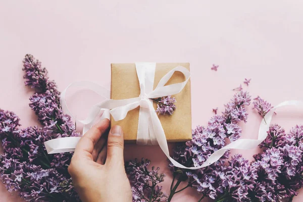 Mão Segurando Caixa Presente Com Fita Flores Lilás Fundo Rosa — Fotografia de Stock