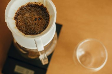 Kağıt filtredeki taze aromatik kahveyi hazırlıyorum. Alternatif kahve, v60 yakın çekim. Barista kahverengi arka planda filtre kahve yapıyor.