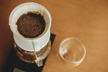 Damlatan kahve. Kağıt filtredeki taze aromatik kahveyi hazırlıyorum. Alternatif kahve, v60 yakın çekim. Barista kahverengi arka planda filtre kahve yapıyor.