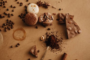 Kahve kalıntısı ve kavrulmuş fasulye, kaşık üzerinde öğütülmüş kahve, makaron, çikolata, kahverengi arka planda tarçın. Kahve karamsar imajı